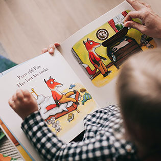 Child reading an illustrated storybook about a fox.